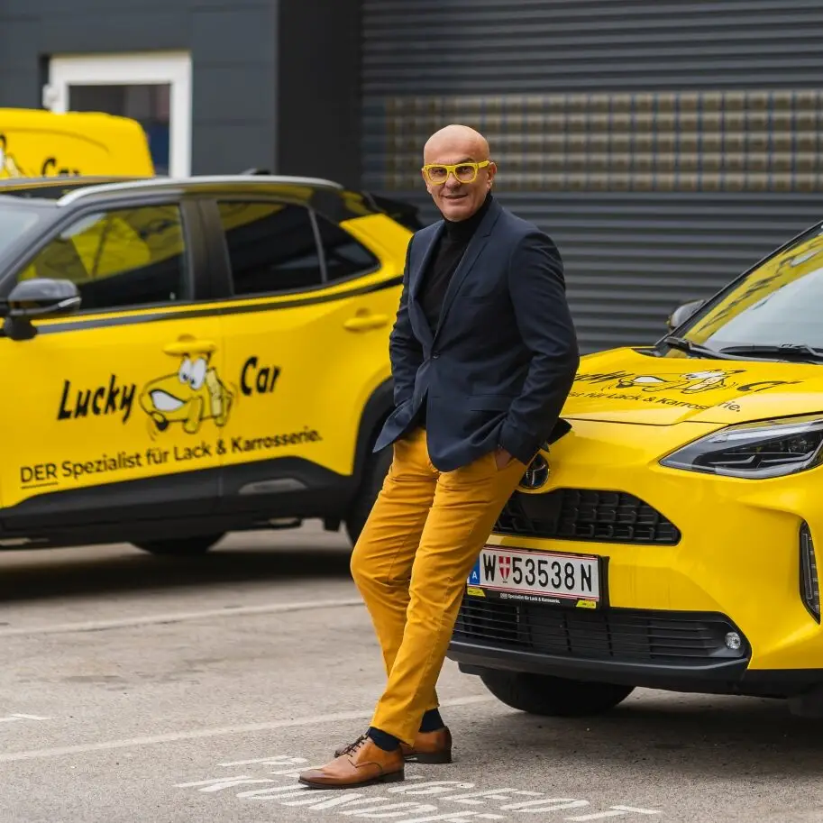 Ossi Matic vor einem gelben Lucky Car Auto