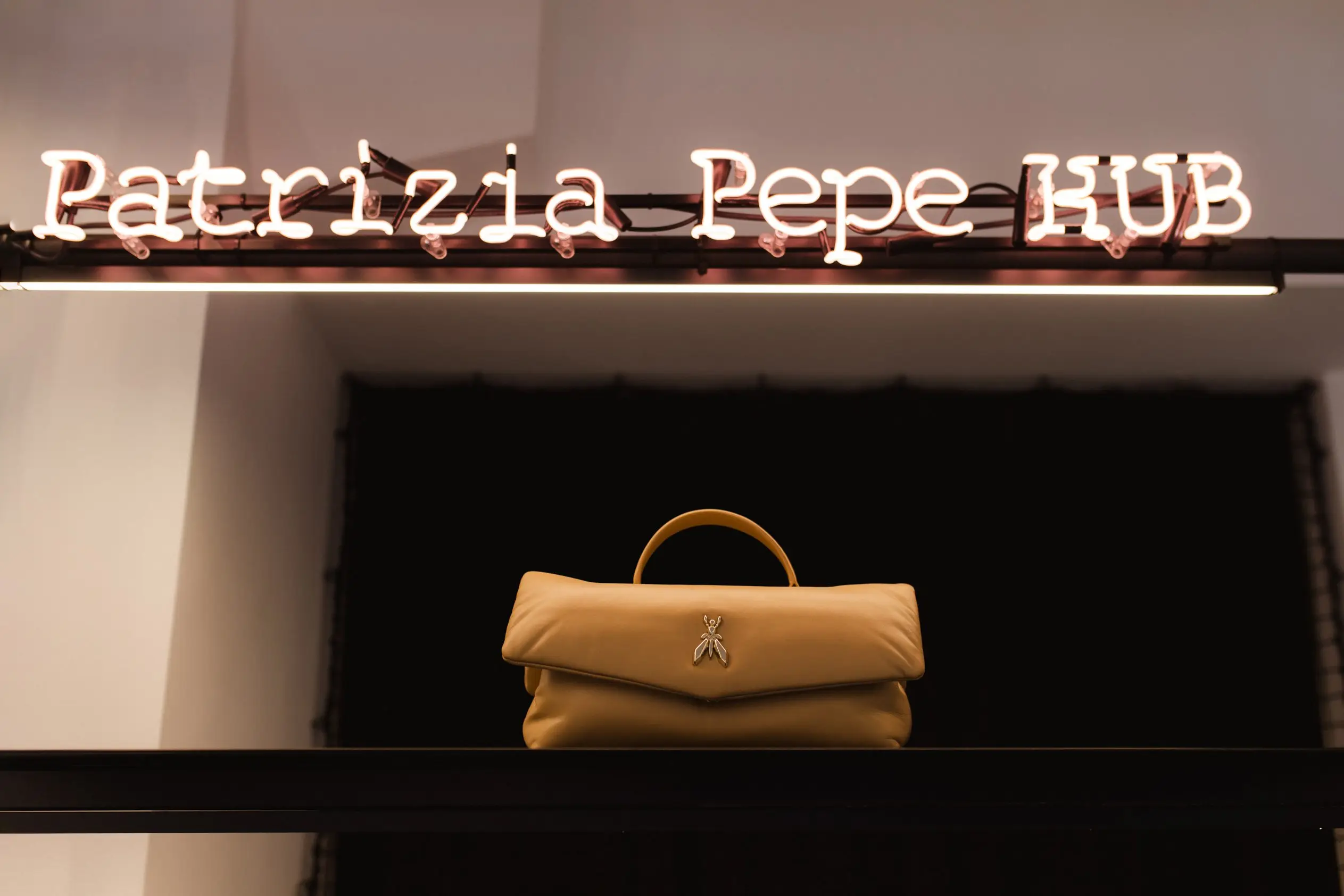 Gelbe Handtasche vor Patrizia Pepe Markenlogo im Fashion Store